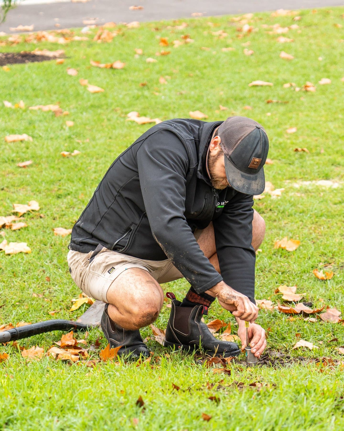Lachlan adjusting an irrigation sprinkler within a landscaped lawn area